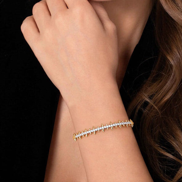 A 14K yellow gold cuff bracelet featuring a central row of clear pavé-set diamonds and multiple pointed spike accents on both sides, shown on a plain white background.