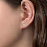 A close-up of a model's ear wearing a clover cutout stud earring in 14K yellow gold with diamonds. 