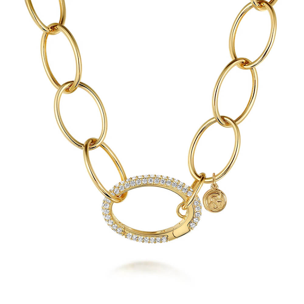 A gold link chain necklace featuring a central oval clasp encrusted with clear diamonds, with a small round charm, set against a clean white background.