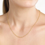 A close-up of a model's neck and upper chest wearing a delicate 14K yellow gold chain hollow oval link necklace.