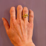 Hand wearing a 14K gold ring on a plain background