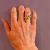 Hand wearing a 14K gold ring on a plain background