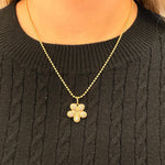 Gold necklace with a floral pendant on a black sweater