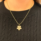 Gold necklace with a floral pendant on a black sweater