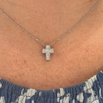 14K white gold cross necklace with diamonds on a person's neck