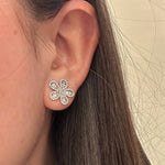 Close-up of a woman wearing a 14K white gold floral diamond earring against a neutral background
