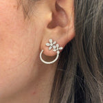 Close-up of a woman's ear wearing a 14K white gold open circle diamond flower stud earring