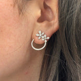 Close-up of a woman's ear wearing a 14K white gold open circle diamond flower stud earring