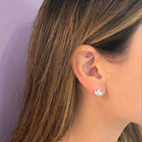 A close-up of a woman's ear wearing a small 14K yellow gold stud earring with three marquise diamonds arranged in a leaf or clover-like shape.
