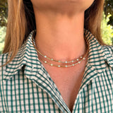 A close-up of a woman wearing a delicate double-layered 14K gold necklace with small bezel diamonds 