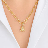 A gold chain necklace with a 14K gold beetle pendant, worn on a model's neck over a white collared shirt.