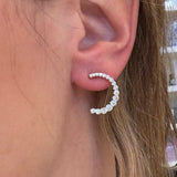Close-up of a woman wearing a C-shaped diamond earring with a blurred background