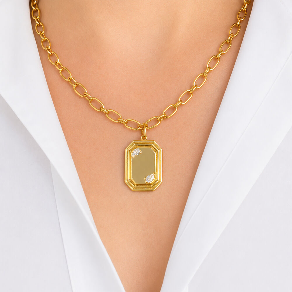A gold chain necklace with a 14K gold rectangular pendant featuring a small clear diamonds, shown worn on a model's neck over a white collared shirt.