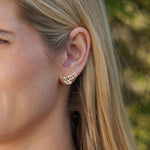 Close-up of a woman's ear wearing a 14K gold leaf shaped earring with diamonds 