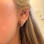 Close-up of a woman wearing a leaf-shaped 14K gold earring with diamonds 