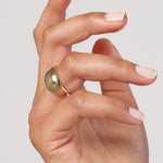 Hand wearing a 14K gold Dome ring on a plain background