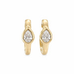 A pair of 14K gold huggie hoop earrings with pear-cut clear diamonds in the center, shown on a plain white background.