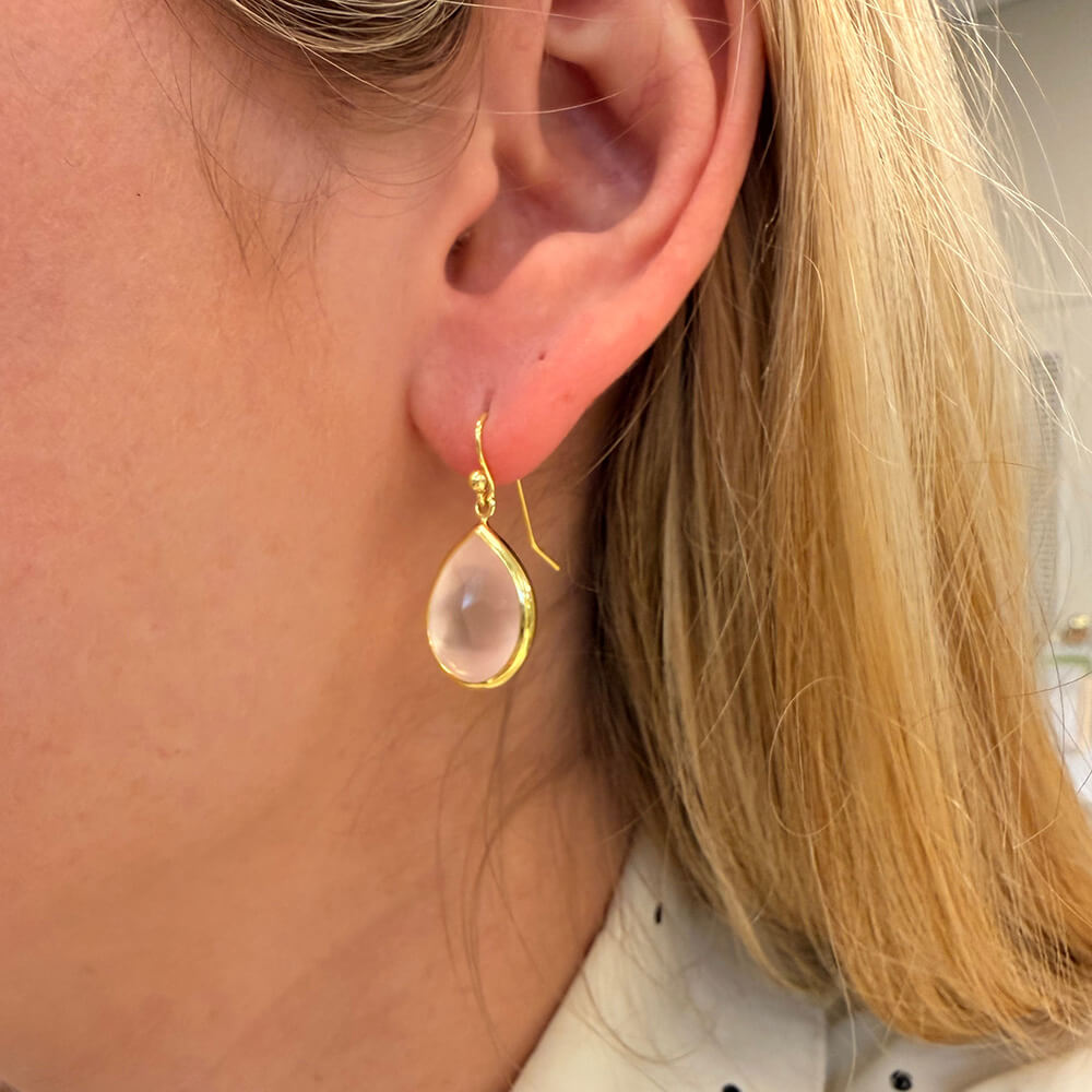 Close-up of a woman wearing a 14K gold rosequartz drop earring