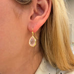 Close-up of a woman wearing a 14K gold rosequartz drop earring