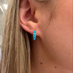 Close-up of an ear with a turquoise earring,
