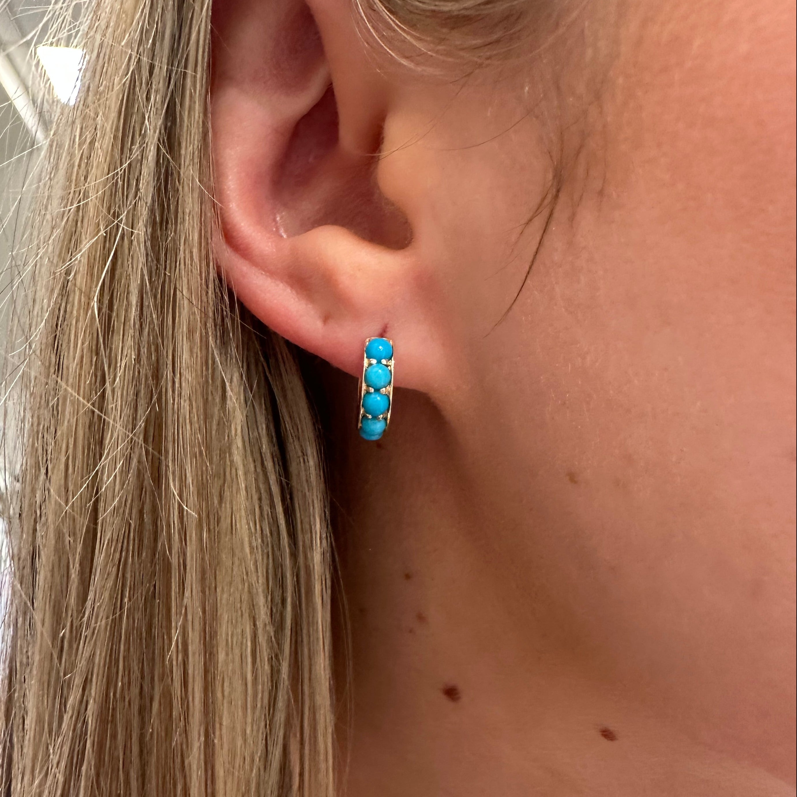 Close-up of an ear with a turquoise earring,