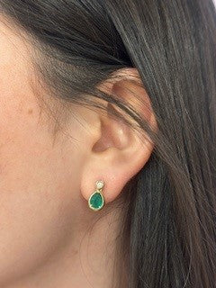 Close-up of an ear wearing a green earring with dark hair in the background