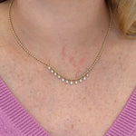 14K Gold necklace with diamonds worn by a woman against a pink sweater background