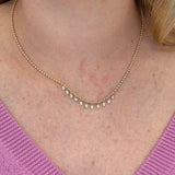 14K Gold necklace with diamonds worn by a woman against a pink sweater background