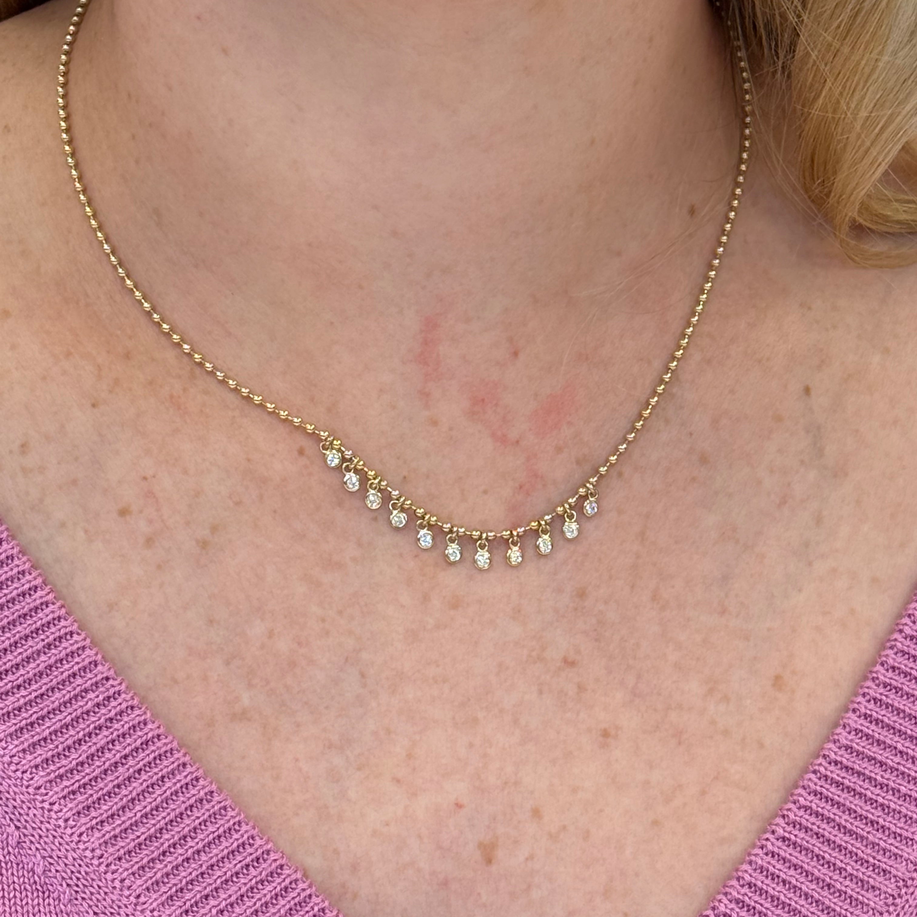 14K Gold necklace with diamonds worn by a woman against a pink sweater background