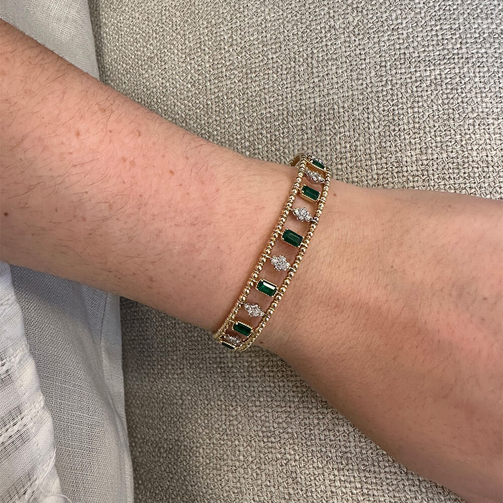 14k gold diamond and emerald bangle on a wrist