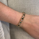 14k gold diamond and emerald bangle on a wrist