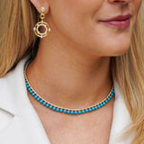 Close-up of a woman wearing a diamond and turquoise necklace.