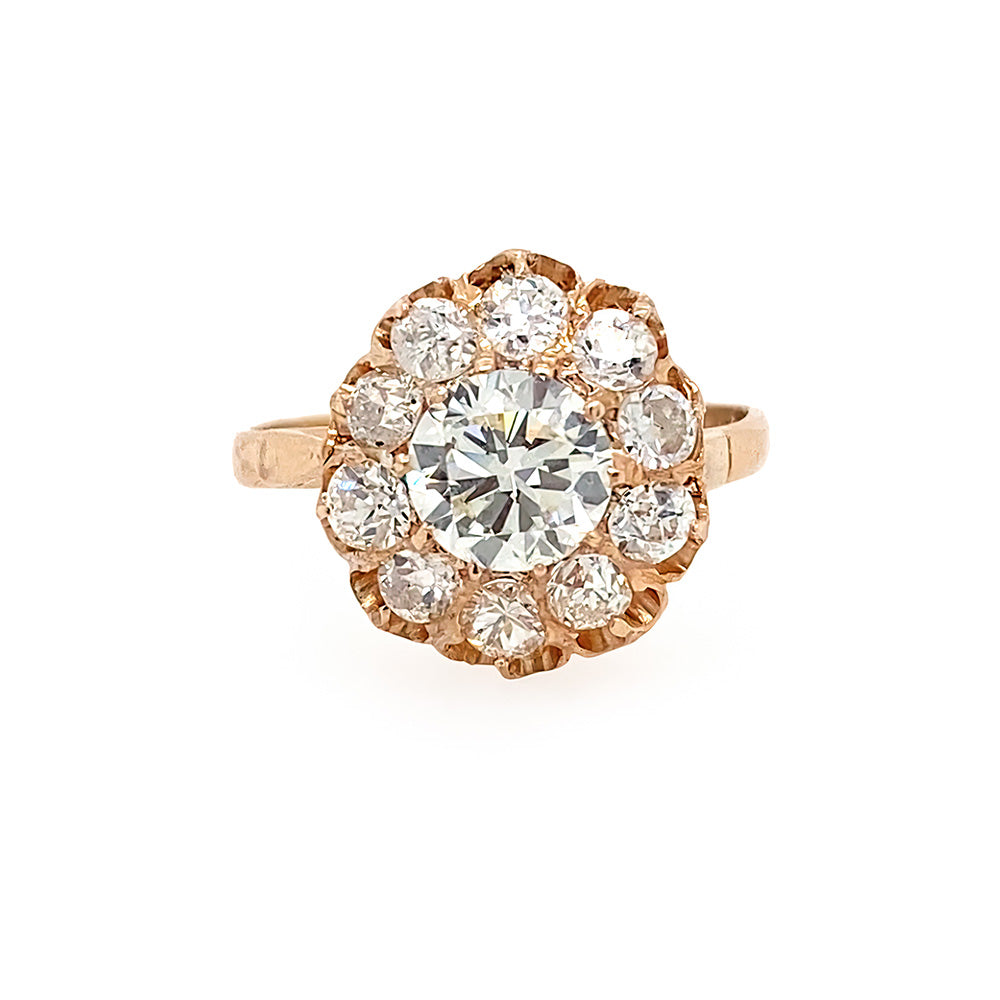 A vintage-style 14k rose gold ring featuring a large round clear center diamond surrounded by a halo of smaller round diamonds, set against a plain white background.