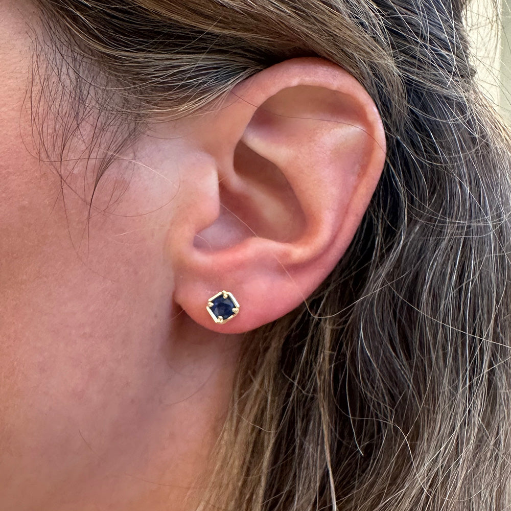 Woman wearing 14K yellow gold bezel sapphire stud earrings