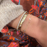 Close-up of a wrist wearing several gold  and diamond bracelets 