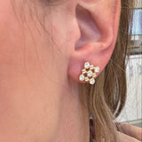 Close-up of an ear wearing a gold earring with small diamond stones.