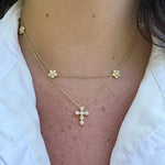 A close-up of a woman wearing a delicate 14K gold diamond cross pendant pendant necklace