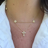 A close-up of a woman wearing a delicate 14K gold diamond cross pendant pendant necklace