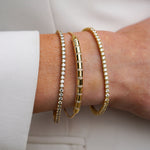 Close-up of a wrist wearing gold  bracelets on a light background