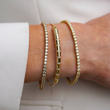 Close-up of a wrist wearing gold  bracelets on a light background