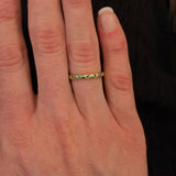 Woman wearing a 14K gold ring with emerald gemstones on a blurred background