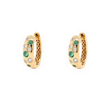 A pair of 18K gold huggie hoop earrings decorated with round-cut green emeralds and clear diamonds, shown against a plain white background.