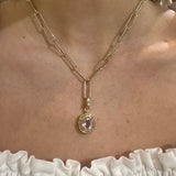 14K Gold necklace with a pendant on a woman's neck against a neutral background