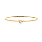 A 14K yellow gold bangle bracelet with a single diamond centerpiece, set on a white background.