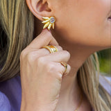 Close-up of a woman wearing gold earrings and rings with a blurred background