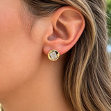 A close-up of a woman's ear wearing a 14k yellow gold stud earring with a clear baguette-cut diamond.