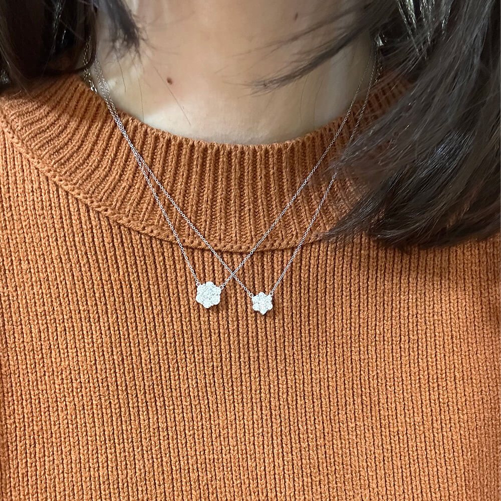 Necklaces with Diamond Cluster pendants on a woman wearing a burnt orange sweater.