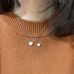 Necklaces with Diamond Cluster pendants on a woman wearing a burnt orange sweater.