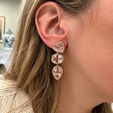 A close-up of a woman's ear wearing a 14k yellow gold drop earring with three pink Morganite gemstone drops.