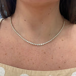 Close-up of a 14K gold bezel set diamond tennis necklace on a woman's neck 